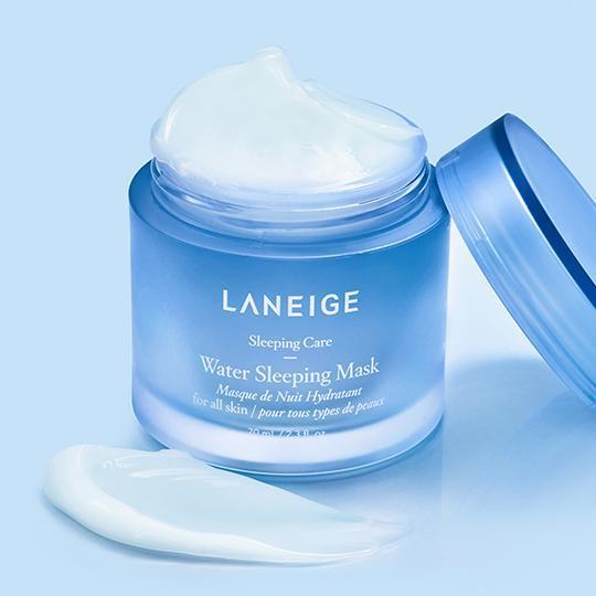 A blue jar of LANEIGE Water Sleeping Mask - 70ml is open, revealing the product inside, with some of it spread on the surface next to it. The label indicates it is for all skin types and part of the Sleeping Care line, containing hyaluronic acid for enhanced skin hydration. The background is light blue.