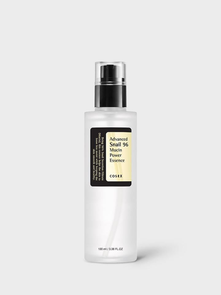 A bottle of COSRX - Advanced Snail 96 Mucin Power Essence 100ml, known for its intense hydration and anti-aging benefits, is displayed against a plain light grey background. The tall, slim bottle has a black pump dispenser and a label showcasing the product name and details. The bottle capacity is 3.38 fl. oz (100 ml).