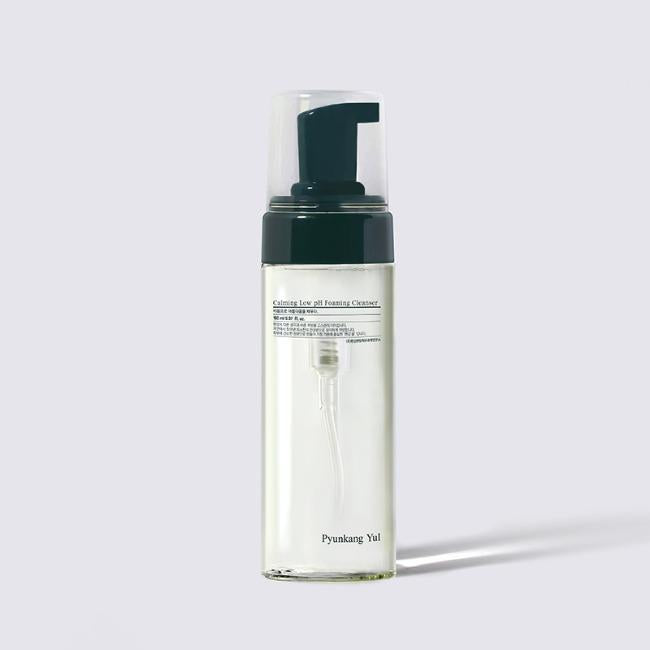 The image shows a clear bottle of PYUNKANGYUL PYUNKANG YUL - Calming Low pH Foaming Cleanser 150ml, ideal for sensitive skin. It has a black pump top and transparent cap. The bottle is filled with a clear liquid and features text and branding in black and gray on the front label, highlighting its pH-balancing benefits.