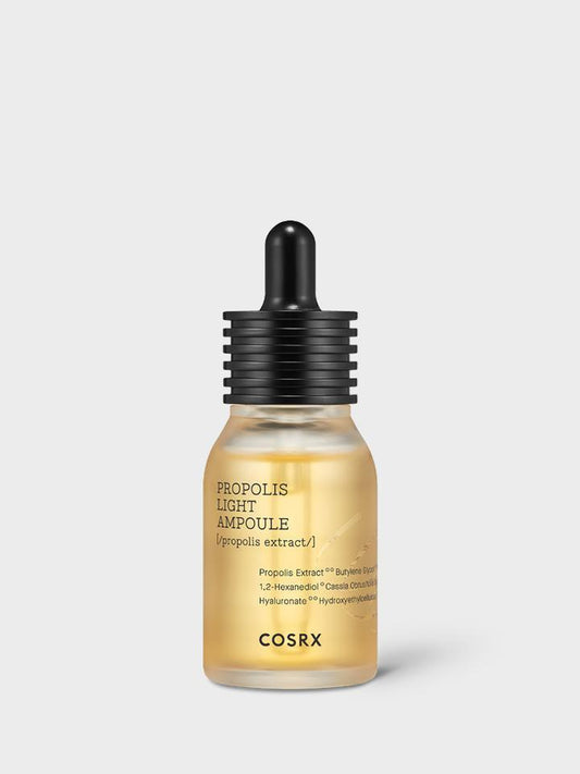 A small, gold-toned bottle of COSRX - Full fit Propolis Light Ampoule 30ml with a black dropper cap. The label showcases the product name and ingredients, emphasizing the black bee propolis extract. This hypoallergenic-tested formula is designed for skincare purposes and has a sleek, minimalist design.