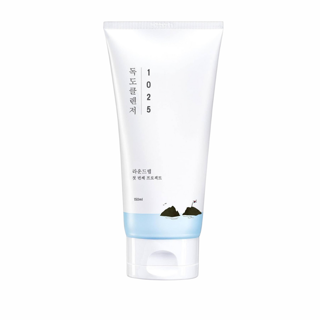 A white tube of skincare product labeled "ROUNDLAB - 1025 Dokdo Cleanser 150ml" with Korean text. The tube has a blue gradient bottom and contains 150ml. This low pH cleanser, suitable for all skin types, features a minimalistic design with a small graphic of islands near the base.