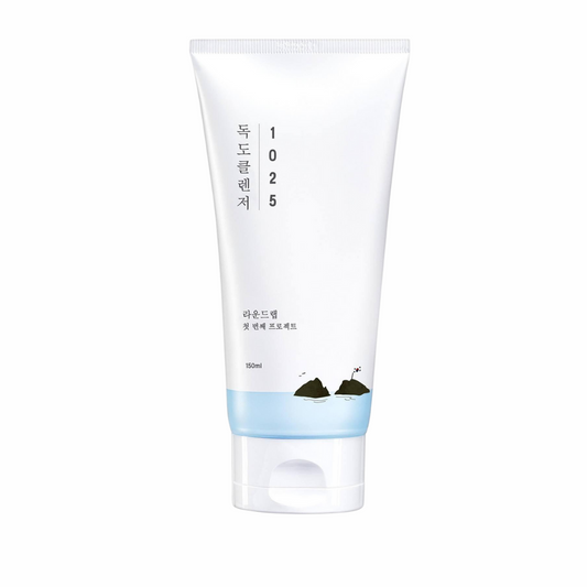 A white tube of skincare product labeled "ROUNDLAB - 1025 Dokdo Cleanser 150ml" with Korean text. The tube has a blue gradient bottom and contains 150ml. This low pH cleanser, suitable for all skin types, features a minimalistic design with a small graphic of islands near the base.