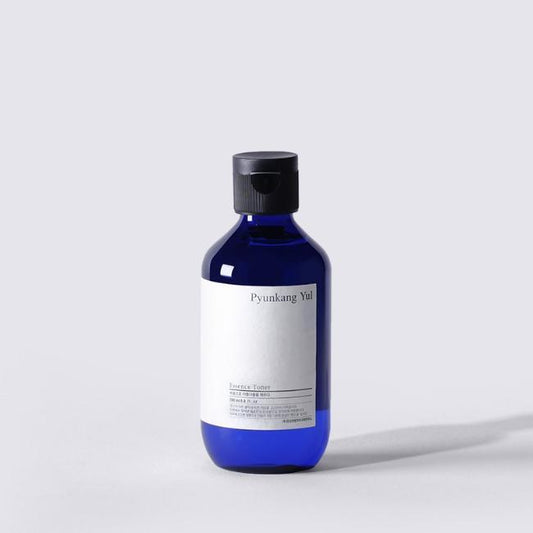 A blue bottle of PYUNKANGYUL - Essence Toner 200ml with a black cap is set against a plain white background. The label on the bottle is white with black text, featuring the brand name and product information. The toner boasts an intensely hydrating formula that revitalizes skin with nutrient-filled moisture.