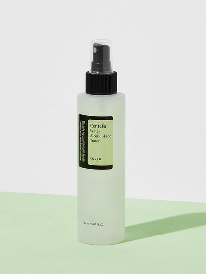 A bottle of COSRX - Centella Water Alcohol-Free Toner 150ml, enriched with soothing & hydrating Centella Asiatica from Jeju Island, is shown against a white and light green background. The cylindrical, translucent bottle features a black spray nozzle and a green label with white text. It holds 150 ml (5.07 fl. oz.).