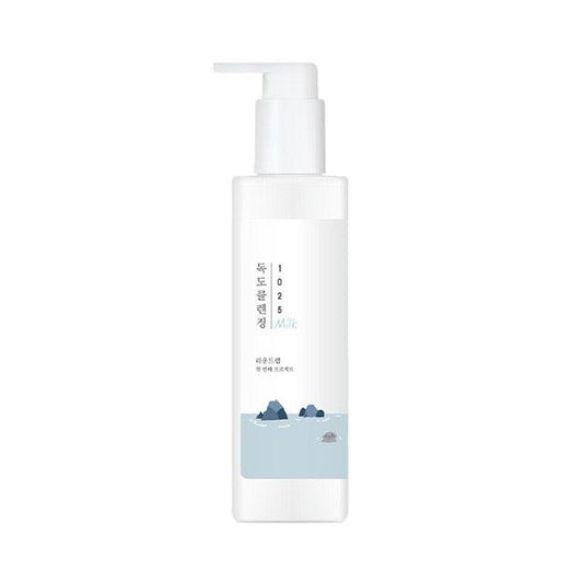 A white pump bottle of ROUNDLAB - 1025 Dokdo Cleansing Milk 200ml, designed for sensitive skin, is shown. The bottle features a minimalist design with Korean text and a light blue illustration of mountains and water at the bottom, infused with ceramide.